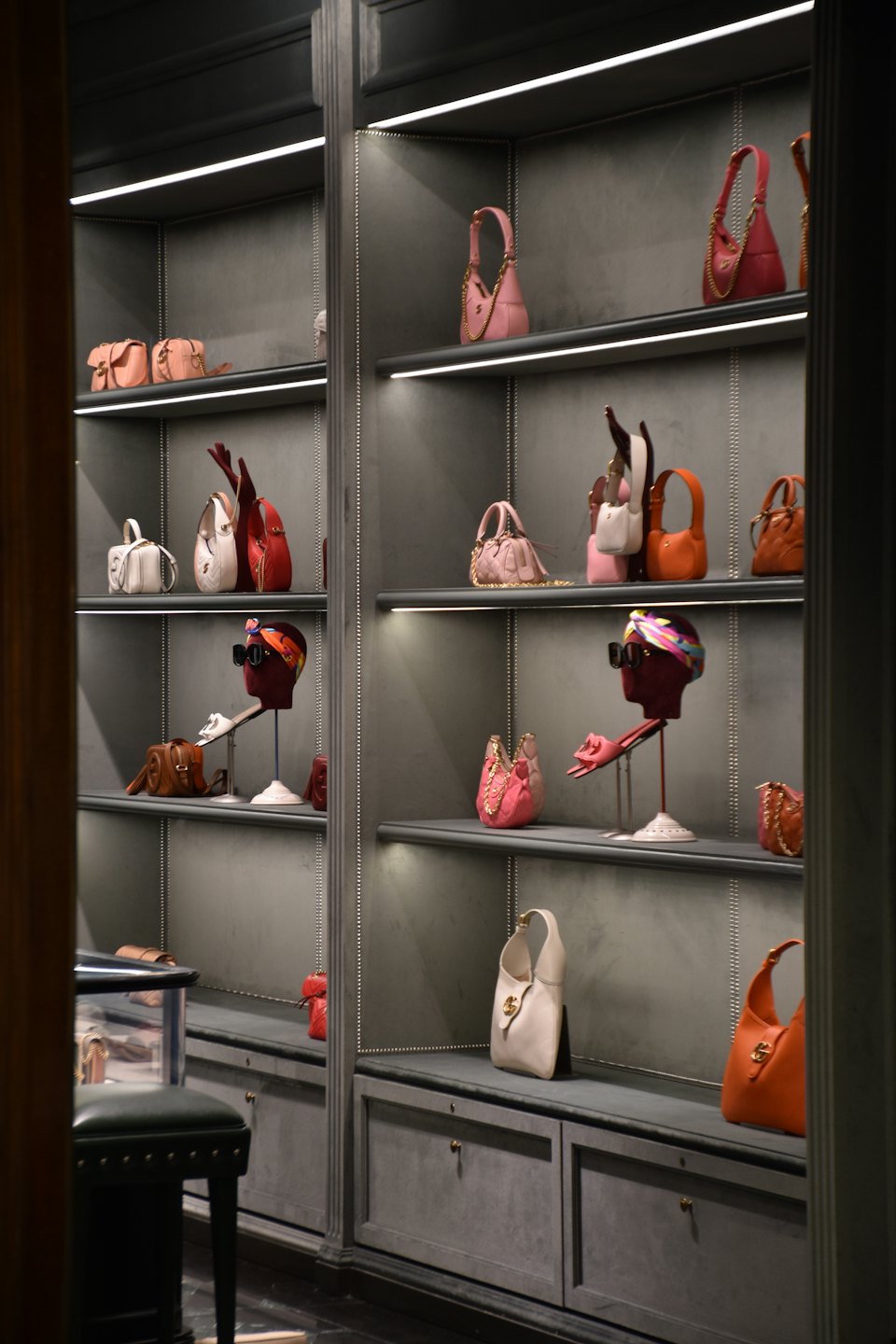 Luxury handbags and accessories displayed on illuminated boutique shelves.